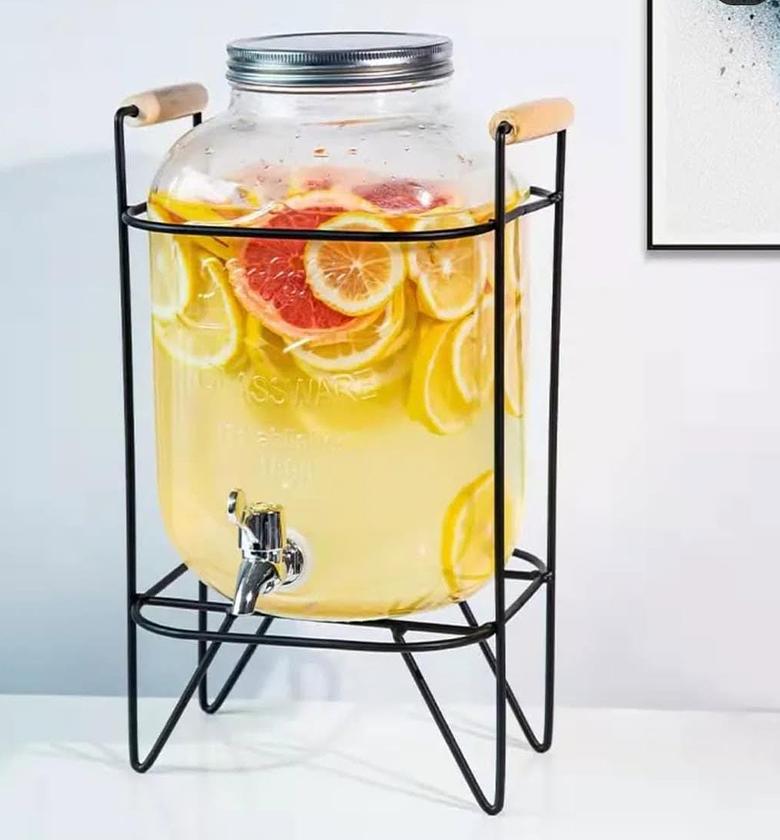 Glass juice dispenser with metallic stand. image