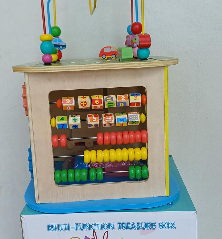 Wooden Activity Cube. With Several Activities, such as a bead maze on top, an abacus, a clock, shape sorters, and turning gears.  image